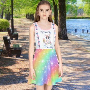 Pink girl's sundress with unicorn kitty and rainbow design, “Never Stop Dreaming” message, part of Paisley’s Treasure Chest Collection, lightweight polyester-spandex blend, ideal for summer and special occasions, girl in unicorn kitty sundress
